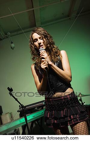 Stock Photograph - Female singing into microphone. Fotosearch