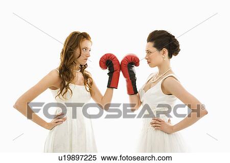 Stock Photography - Caucasian bride and Asian bride holding boxing gloves up to each other.. Fotosearch