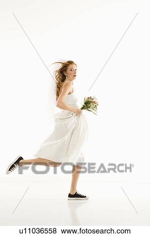 Stock Photo - Caucasian bride running and holding bouquet.. Fotosearch