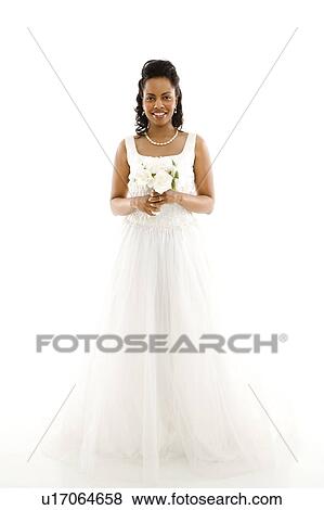 Stock Photo - Mid-adult African-American bride holding bouquet on white background. . Fotosearch
