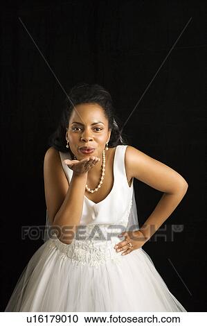 Stock Image - Mid-adult bride blowing a kiss. Fotosearch