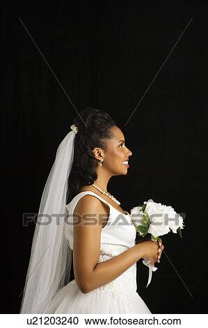 Stock Image - Portrait of a mid-adult African-American bride on black background.. Fotosearch