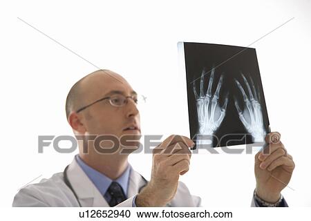 Caucasian mid adult male physician holding up hand xrays. View Large Photo Image Stock Image - Caucasian mid adult male physician holding up hand xrays.. Fotosearch