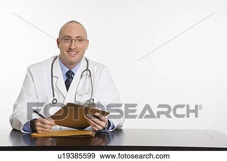 Caucasian mid adult male physician sitting at desk smiling. View Large Photo Image Stock Photo - Caucasian mid adult male physician sitting at desk smiling.. Fotosearch