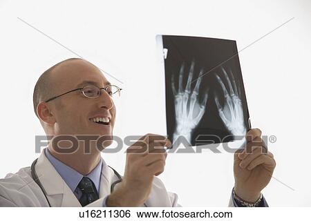 Caucasian mid adult male physician holding up hand xrays. View Large Photo Image Stock Photograph - Caucasian mid adult male physician holding up hand xrays.. Fotosearch