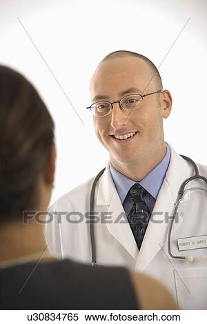 Caucasian mid adult male physician talking with Indian woman patient. View Large Photo Image Stock Photography - Caucasian mid adult male physician talking with Indian woman patient.. Fotosearch