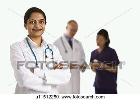 Indian mid adult woman doctor standing with medical staff in background. View Large Photo Image Stock Image - Indian mid adult woman doctor standing with medical staff in background.. Fotosearch