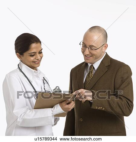 Picture - Indian mid adult woman doctor talking with man in business suit.. Fotosearch