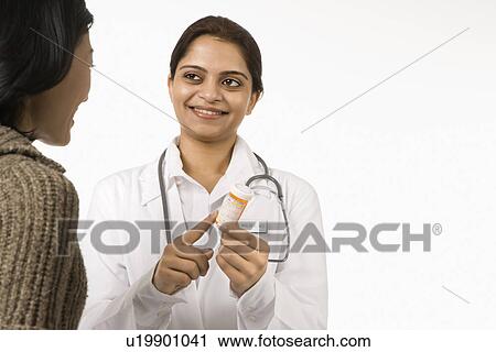 Indian woman doctor explaining medication to Asian woman patient. View Large Photo Image Stock Image - Indian woman doctor explaining medication to Asian woman patient.. Fotosearch