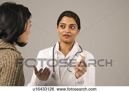 Indian woman doctor explaining medication to Asian woman patient. View Large Photo Image Stock Photograph - Indian woman doctor explaining medication to Asian woman patient.. Fotosearch