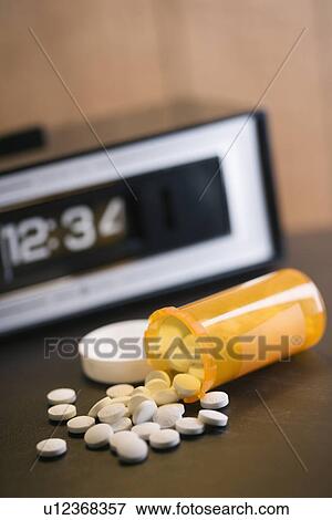 Open medicine bottle with pills spilling out onto table with clock in background. View Large Photo Image Stock Photo - Open medicine bottle with pills spilling out onto table with clock in background.. Fotosearch
