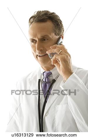 Stock Photo - Portrait of a mid-adult Caucasian male doctor with stethoscope around his neck talking on cell phone.. Fotosearch