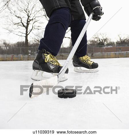 Boy in ice hockey uniform skating on ice rink moving puck View Large Photo Image Stock Photo - Boy in ice hockey uniform skating on ice rink moving puck. Fotosearch