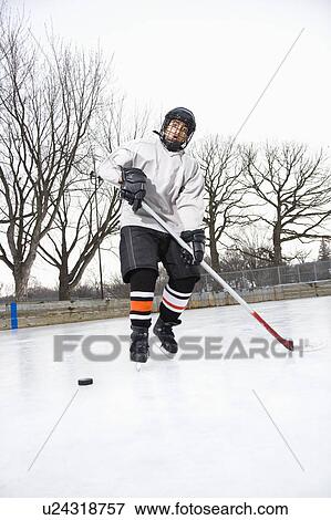 Boy in ice hockey uniform skating on ice rink moving puck. View Large Photo Image Stock Photo - Boy in ice hockey uniform skating on ice rink moving puck.. Fotosearch