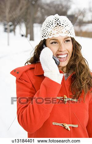 Stock Image - Caucasian young adult female on cell phone outdoors in the snow.. Fotosearch