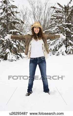 Stock Photo - Caucasian young adult female standing with arms outstretched in snow wearing straw cowboy hat.. Fotosearch