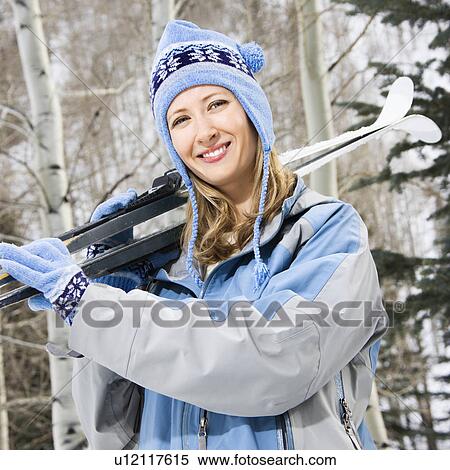 Stock Photography - Female skier carrying skis on shoulder. Fotosearch
