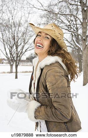 Stock Photo - Female smiling at viewer while holding snowball and wearing straw cowboy hat.. Fotosearch