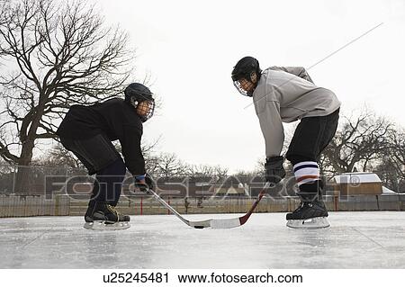 Stock Image - Two ice hockey player boys in uniform facing off on ice.. Fotosearch