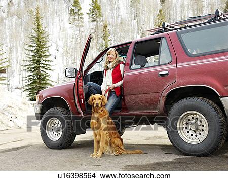 Woman with dog sitting with dirt splattered SUV automobile in snowy rural setting. View Large Photo Image Picture - Woman with dog sitting with dirt splattered SUV automobile in snowy rural setting.. Fotosearch