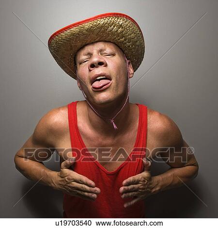 Stock Image - Portrait of a mid-adult Caucasian male wearing straw hat and touching his chest.. Fotosearch