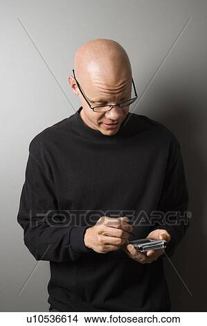 Portrait of mid-adult man holding PDA View Large Photo Image Picture - Portrait of mid-adult man holding PDA. Fotosearch