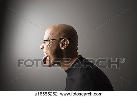 Stock Image - Profile portrait of mid-adult Caucasian male sticking out tongue.. Fotosearch