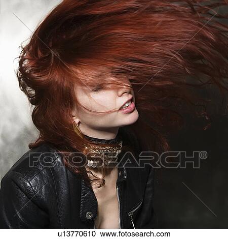 Stock Image - Caucasian woman in leather jacket tossing long hair in air. . Fotosearch