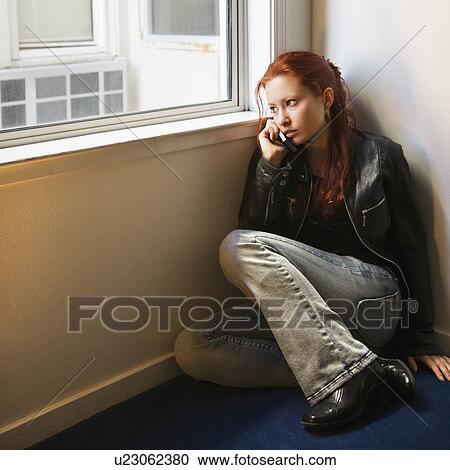 Pretty redhead young woman sitting on floor indoors looking out window holding cellphone to ear. View Large Photo Image Stock Image - Pretty redhead young woman sitting on floor indoors looking out window holding cellphone to ear.. Fotosearch