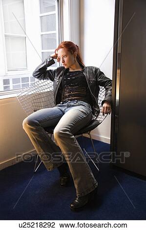 Pretty redhead young woman sitting indoors on metal chair by window looking out View Large Photo Image Stock Image - Pretty redhead young woman sitting indoors on metal chair by window looking out. Fotosearch