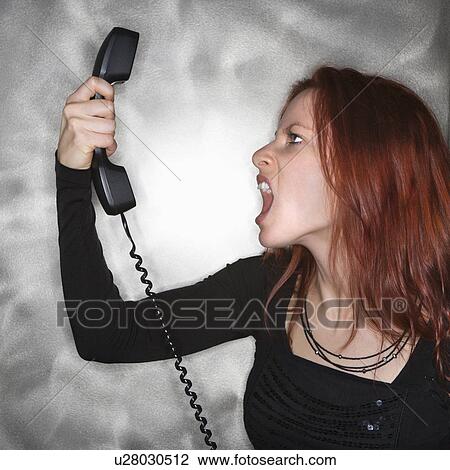 Stock Image - Woman holding telephone and yelling. Fotosearch