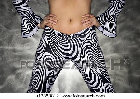 Stock Image - Woman showing midriff with hands on hips. Fotosearch