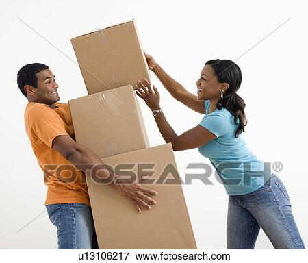 Stock Photo - African American woman placing boxes on large stack man is holding.. Fotosearch
