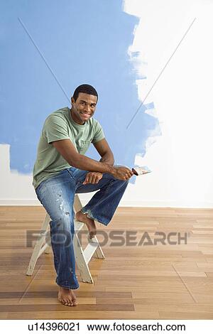 African American young man sitting next to half-painted wall with paintbrush. View Large Photo Image Stock Image - African American young man sitting next to half-painted wall with paintbrush.. Fotosearch