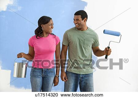 Couple next to half-painted wall with paint supplies View Large Photo Image Stock Image - Couple next to half-painted wall with paint supplies. Fotosearch
