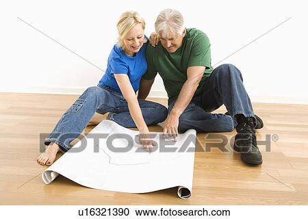 Couple sitting on floor looking at and discussing architectural blueprints together View Large Photo Image Stock Image - Couple sitting on floor looking at and discussing architectural blueprints together. Fotosearch