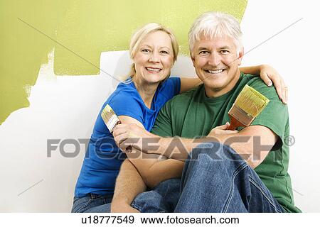 Couple snuggling in front of wall they are painting green View Large Photo Image Stock Photo - Couple snuggling in front of wall they are painting green. Fotosearch
