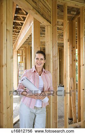 Female holding blueprints on building construction site View Large Photo Image Stock Photograph - Female holding blueprints on building construction site. Fotosearch