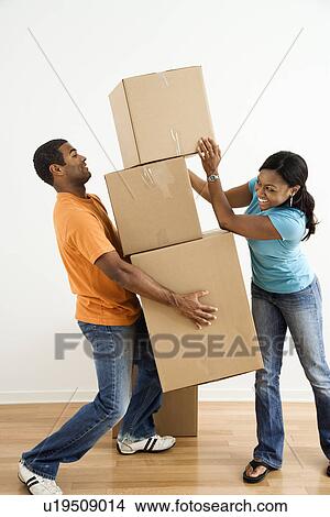 Picture - Female placing boxes on large stack man is holding. Fotosearch