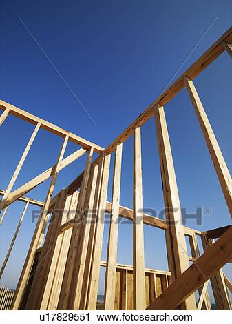 Stock Image - Low angle view of new construction framework for house with blue sky . Fotosearch
