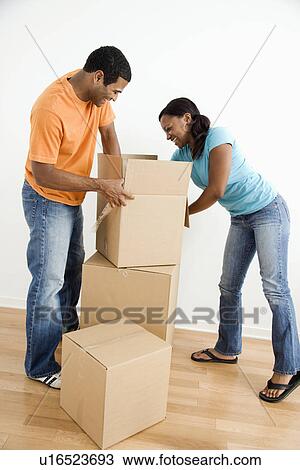 Stock Image - Male and female couple packing cardboard boxes. Fotosearch