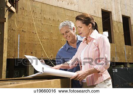 Male and female looking at blueprints in construction phase of house View Large Photo Image Stock Photograph - Male and female looking at blueprints in construction phase of house. Fotosearch