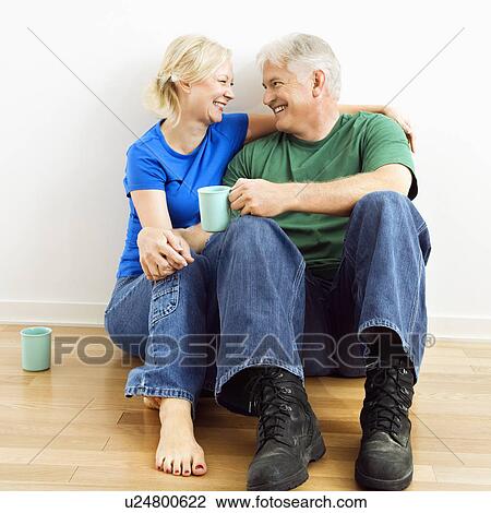 Middle-aged couple sitting on floor snuggling and drinking coffee. View Large Photo Image Stock Image - Middle-aged couple sitting on floor snuggling and drinking coffee.. Fotosearch