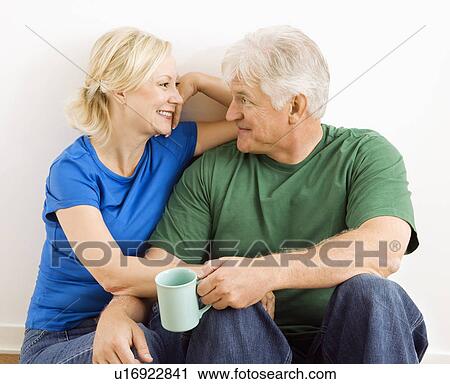 Middle-aged couple sitting together snuggling and drinking coffee. View Large Photo Image Stock Image - Middle-aged couple sitting together snuggling and drinking coffee.. Fotosearch