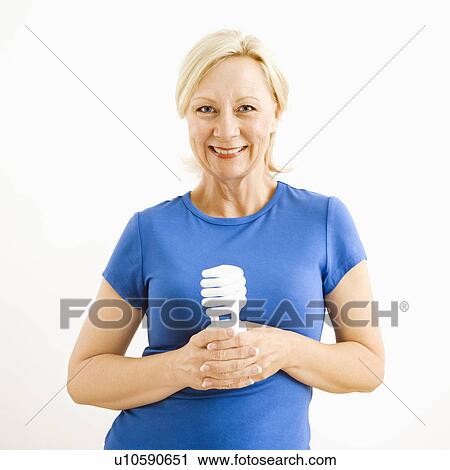 Stock Image - Portrait of smiling adult blonde woman holding energy-saving lightbulb.. Fotosearch