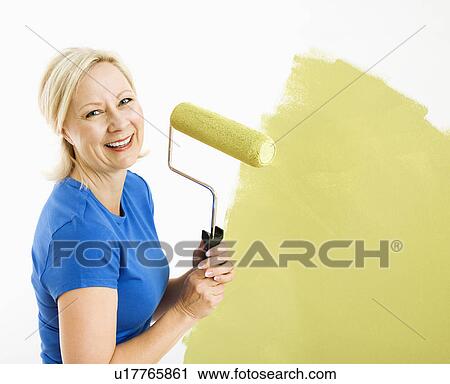 Woman painting wall green with paint roller smiling at viewer View Large Photo Image Stock Image - Woman painting wall green with paint roller smiling at viewer. Fotosearch