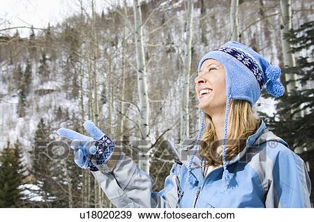 Stock Photo - Attractive smiling mid adult Caucasian blond woman wearing blue ski clothing smiling and pointing.. Fotosearch