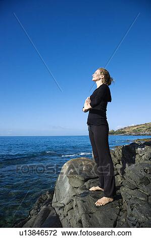 Caucasian mid-adult woman standing on rocky coast of Maui, Hawaii, meditating. View Large Photo Image Stock Image - Caucasian mid-adult woman standing on rocky coast of Maui, Hawaii, meditating.. Fotosearch