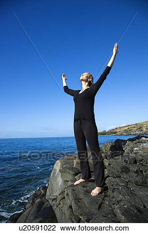 Caucasian mid-adult woman standing on rocky coast of Maui, Hawaii with arms outstretched. View Large Photo Image Stock Image - Caucasian mid-adult woman standing on rocky coast of Maui, Hawaii with arms outstretched.. Fotosearch