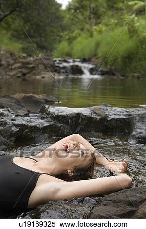 Caucasian young adult woman laying in freshwater stream laughing with arms over head. View Large Photo Image Stock Photography - Caucasian young adult woman laying in freshwater stream laughing with arms over head.. Fotosearch